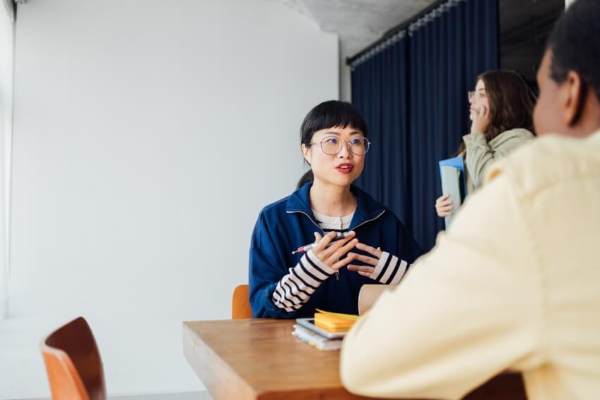 woman at table speaking to person with back to camera