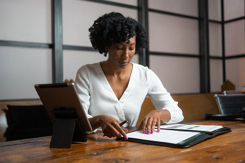 woman sitting at a desk looking at a notebook